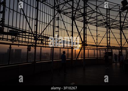 Silhouette von Besuchern, die den Sonnenuntergang von der Aussichtsplattform des Chengdu Tianfu Panda-Turms genießen, mit der Stadt Skyline im Rahmen. Stockfoto