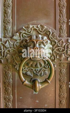 Nahaufnahme eines kunstvoll verzierten bronzenen Löwenkopf-Türklopfers mit aufwendigen gotischen Blumenmotiven an einem historischen Eingang der Burg Hohenzollern, Deutschland. Stockfoto