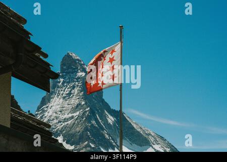 Die Flagge des Kantons Wallis weht mit dem schneebedeckten Matterhorn-Gipfel unter einem klaren blauen Himmel Stockfoto