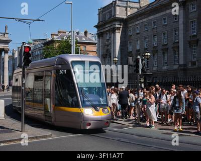 Eine LUAS-Straßenbahn, die am Trinity College in der Stadt Dublin, Irland, vorbeifährt. Stockfoto