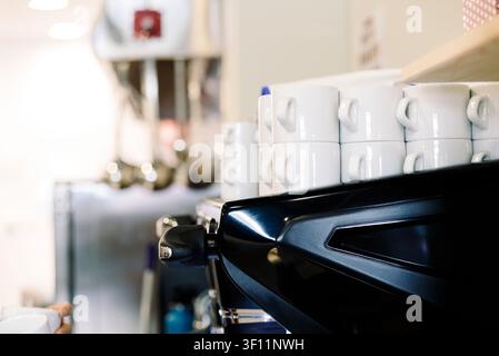 Tassen stehen auf einer Kaffeemaschine in einer Bar, in der Kaffee zubereitet wird, und zeigen eine geschäftige Umgebung und den Brühprozess. Stockfoto