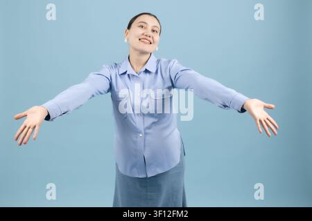 Fröhliche junge Frau steht mit offenen Armen, um Freiheit und Leben zu begrüßen Stockfoto