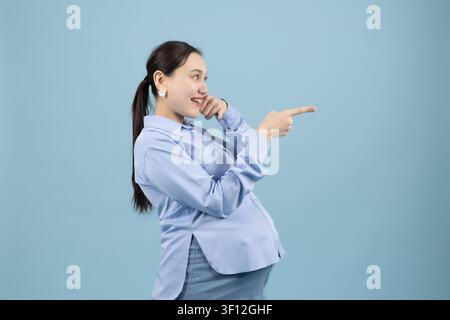 Schwangere Frau, die mit dem Finger weist und Richtung zum Kopierraum zeigt Stockfoto