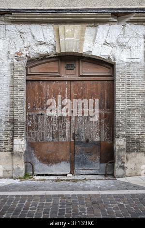 Alte, verwitterte Holztür mit verwittertem Steinbogen in der alten Stadt Troyes, Departement Aube, Region Grand Est, Frankreich Stockfoto