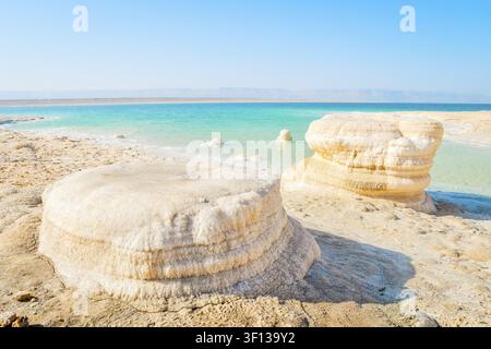 Totes Meer Salz-Kristallformationen am Strand in Jordanien an einem sonnigen Mittag mit türkisfarbenem Wasser an der Wüstenküste. Tiefster Punkt der Erdoberfläche Landschaft. Jor Stockfoto