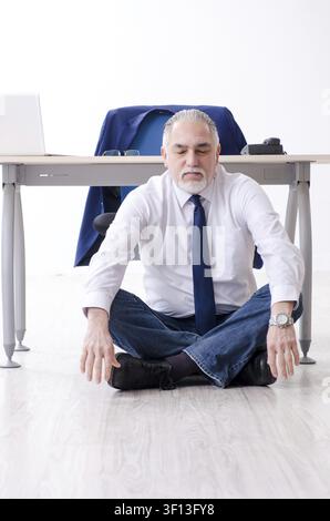 Alter Geschäftsmann Yoga Übungen im Büro Stockfoto