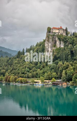 Burg Bled erhebt sich über ihrer bewaldeten Klippe am Lake Bled unter den Julischen Alpen in Slowenien. Stockfoto