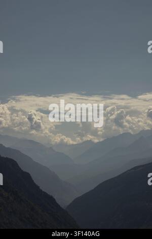 Schichtige Bergkämme, die sich in dunstigen Tälern unter einem bewölkten Himmel zurückziehen Stockfoto