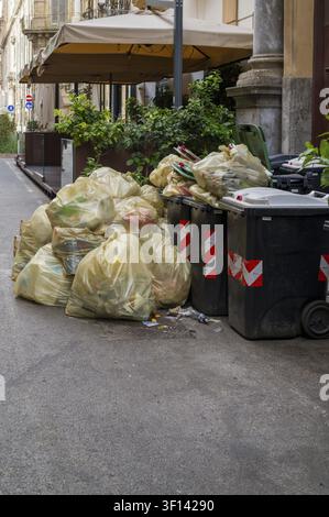 Ein Fußgänger spaziert an Müllhaufen vor Osteria Villena in Palermo vorbei, wo überfüllte Müllsäcke die anhaltende Herausforderung der kommunalen Abwasserentsorgung widerspiegeln Stockfoto