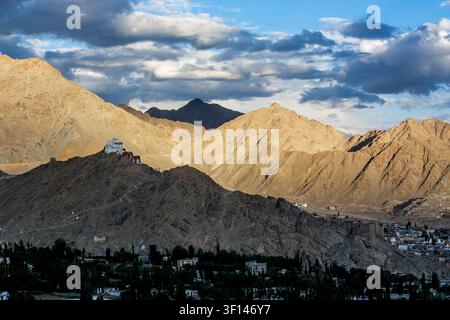 Eine Panoramaansicht zeigt das Namgyal Tsemo Kloster, das auf einem trockenen Hügel thront, während sich die Stadt Leh in das Tal zwischen dichten grünen Bäumen erstreckt Stockfoto