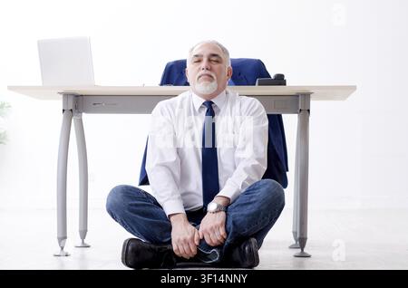 Alter Geschäftsmann Yoga Übungen im Büro Stockfoto