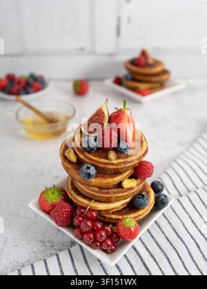 Hoher Stapel selbstgemachter Pfannkuchenwaffeln, serviert mit frischen Beeren, Feigen und saisonalem Obst Stockfoto