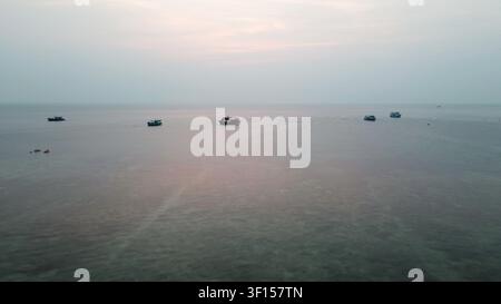 Boote überqueren ein ruhiges Meer bei Sonnenuntergang, Luftbild einer friedlichen Meereslandschaft Stockfoto