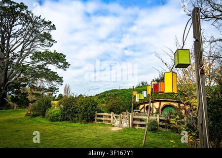 Bunte Partylaternen hängen vor einem rustikalen Hobbit-Haus mit einer grünen Tür am ikonischen Hobbiton-Filmset in Matamata, Neuseeland. Stockfoto