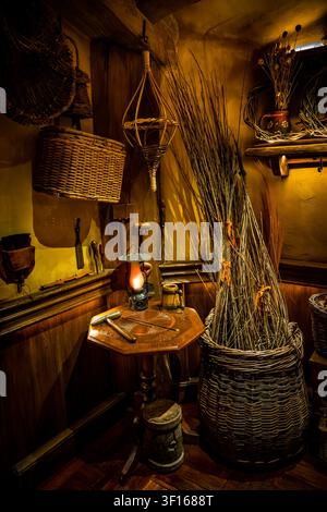 Eine gemütliche Innenecke eines rustikalen Hobbit-Hauses am Filmset von Hobbiton, mit handgeflochtenen Weidenkörben, einem kleinen Holztisch mit Werkzeugen. Stockfoto