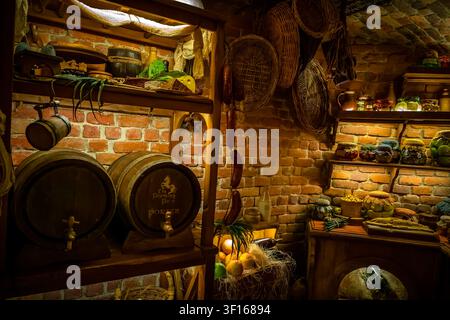 Gemütliches Interieur einer rustikalen Fantasy-Vorratskammer gefüllt mit hölzernen Fässern, hängenden Weidenkörben und Regalen voller eingelegter Gläser. Stockfoto