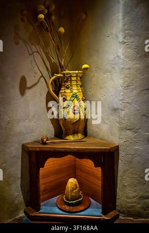 Eine rustikale Eckauslage in einem Hobbit-Haus im Hobbiton-Filmset in Matamata, Neuseeland, mit einem dekorativen gelben Keramikkanister. Stockfoto