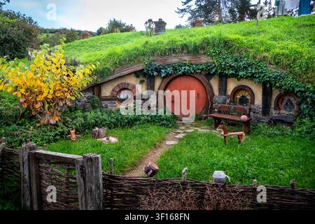 Bezauberndes rustikales Hobbit-Haus mit einer runden roten Tür am Hobbiton-Filmset in Neuseeland Stockfoto