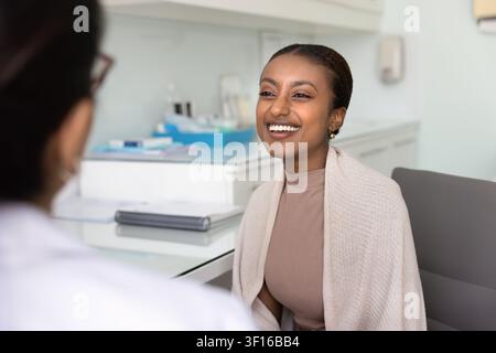 Fröhliche schöne junge afrikanische Patientin spricht mit einer Ärztin Stockfoto