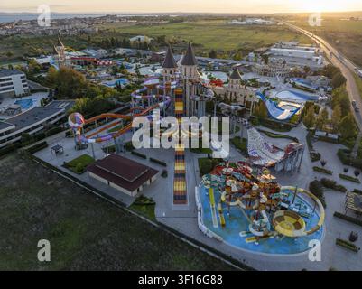 Luftaufnahme eines großen Wasserparks mit bunten Wasserrutschen, Schwimmbecken und schlossartigen Gebäuden während der Goldenen Stunde in Bulgarien. Stockfoto