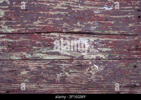 Verwitterte dunkelrote abblätternde Farbe auf alten Holzplanken als Textur Stockfoto