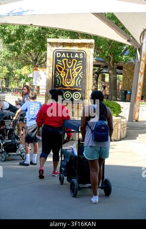 DALLAS, TX, USA - 10. JULI 2026: Menschen mit Kinderwagen gehen am Eingangsschild des Dallas Zoos vorbei. Der Zoo ist eine Hauptattraktion und bietet eine breite Var Stockfoto