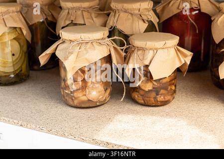 Verschiedene hausgemachte eingelegte Gemüsesorten in Gläsern ordentlich auf Vorratsregalen angeordnet Stockfoto