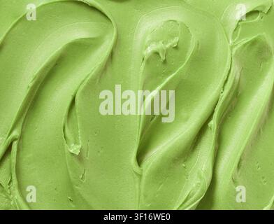 Nahaufnahme einer glatten Pistaziencreme-Textur mit cremigen Wirbeln und sattem Grün. Abstrakter Lebensmittelhintergrund ideal für gesunde Ernährung, Snack c Stockfoto
