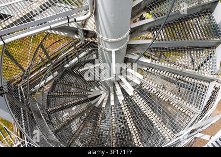 Top-Down-Ansicht einer industriellen Metall-Spiraltreppe mit vergitterten Stufen und zentraler Säule, die ein abstraktes geometrisches Muster bildet, Architektur und Ingenieurwesen Stockfoto