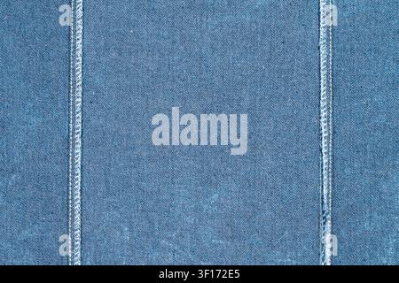 Nahaufnahme von blauem Denimstoff mit sichtbarer weißer Doppelnähten im Gewebe. Strukturierte Oberfläche mit dezenter Verblassung. Ideal für Mode, Textilien, Hintergrund Stockfoto