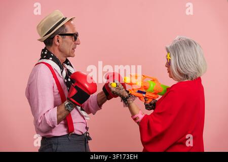 Seniorenpaar hat Spaß beim Boxen und Spielen mit einer Wasserpistole Stockfoto