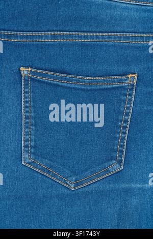 Nahaufnahme der Gesäßtasche klassischer blauer Denimjeans. Gelbe Kontrastnähte auf strukturiertem Stoff. Einfacher, sauberer Hintergrund für Mode, Textil, Stockfoto