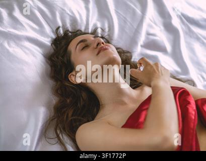 Porträt einer jungen Frau, die im Bett liegt und Parfüm verwendet Stockfoto