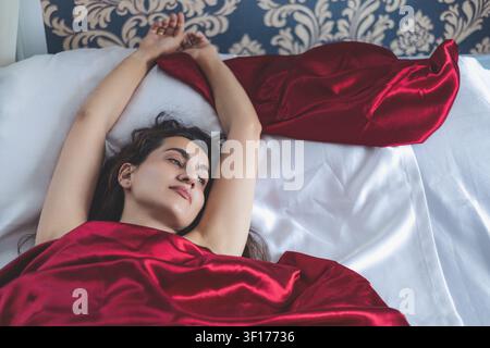 Schöne schlafende Frau in Seidenbettwäsche Stockfoto