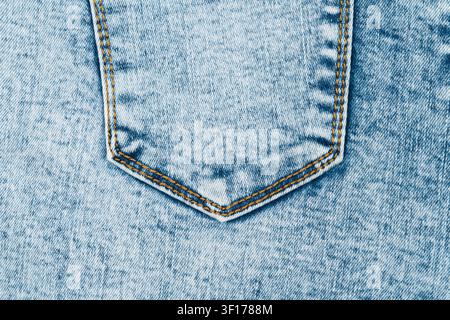 Detaillierte Nahaufnahme einer hellblauen Acid-Wash-Jeans-Tasche. Klassische Denim-Textur mit orangefarbener Kontrastnaht. Minimalistisches Mode-Hintergrund für Bekleidung Stockfoto