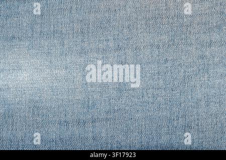 Nahaufnahme von blauem Denimstoff, der die diagonale Köperbindung unter gleichmäßigem weichem Licht zeigt. Kühle Töne und subtile Schatten heben die Materialdetails hervor Stockfoto