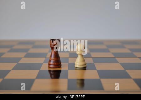 Schwarzer König steht dem weißen Bauern auf dem Schachbrett gegenüber Stockfoto
