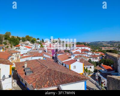 OBIDOS, PORTUGAL - 25. MAI 2025: Luftaufnahme von mittelalterlichen Burgtürmen, Steinmauern und roten Dächern über einer kleinen historischen Stadt, Obidos, Portugal Stockfoto