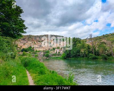 Das alte Steindorf Peyre liegt unterhalb einer großen Felsenwand am ruhigen grünen Fluss Tarn in Aveyron, Frankreich Stockfoto