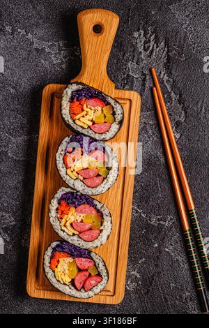 Kimbap (oder Gimbap) mit farbenfrohen Zutaten, serviert auf einem Holzbrett Stockfoto