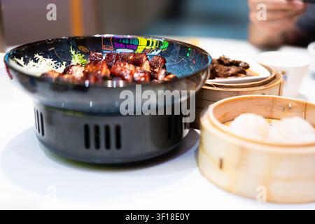 Cantonese Dim Sum Festmahl in Hongkong: Gedämpfte Schweinebrötchen und geröstetes Fleisch in Bambusdampfgarern mit Stockfoto
