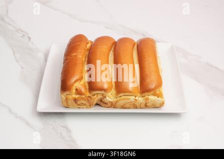 Vier goldbraune Pull-Apart-Brötchen, die auf einem weißen quadratischen Teller über einem Marmorhintergrund angeordnet sind Stockfoto