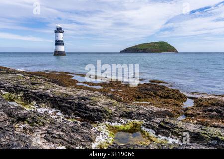 Der historische Leuchtturm Trwyn Du steht vor der rauen Küste von Penmon Point auf der Insel Anglesey in Nordwales. Stockfoto