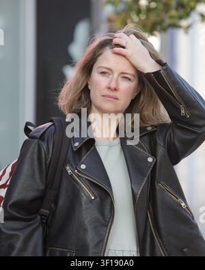 Authentisches Porträt einer gestressten Frau mittleren Alters, die mit besorgtem Gesichtsausdruck und einer Hand am Kopf auf einer Stadtstraße geht. Stockfoto