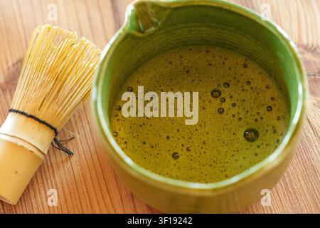 Frisch geschlagener Matcha in einer Keramikschüssel mit Bambusrührer in der Nähe Stockfoto