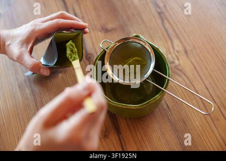 Matcha-Pulver in eine Schüssel sieben für ein selbstgemachtes Eislatterezept Stockfoto