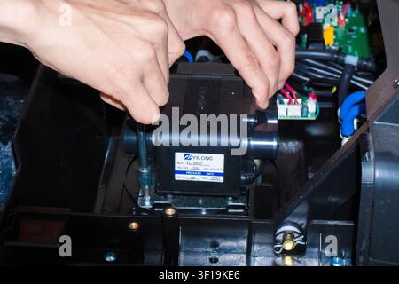 Technischer Ingenieur repariert und misst das elektronische Motherboard eines elektrischen Massagestuhls mit professionellen Werkzeugen, Hardware-Reparaturdienst. Stockfoto