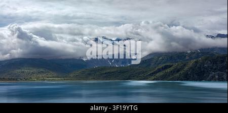Ein majestätisches horizontales Panoramalandchaftsfoto, das tiefhängende Gewitterwolken um schneebedeckte Alpen Gipfel in Glacier Bay, Alaska einfängt Stockfoto