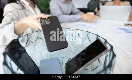 Teilnehmer eines Meetings, der sein Handy in den Bürotelefon-Gefängnis steckt, Nahaufnahme Stockfoto