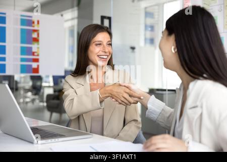 Selbstbewusste Frauen, die sich die Hände schütteln und ein Geschäftsabkommen im Büro besiegeln Stockfoto